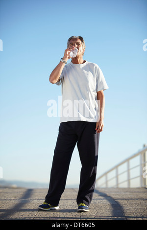 Uomo senior di acqua potabile a piedi Foto Stock