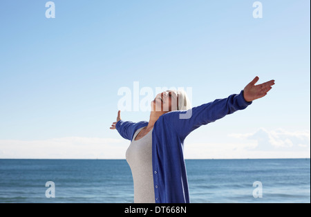 Donna matura sulla spiaggia con bracci estesi