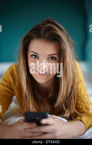 Ritratto di ragazza adolescente in camera da letto con lo smartphone Foto Stock