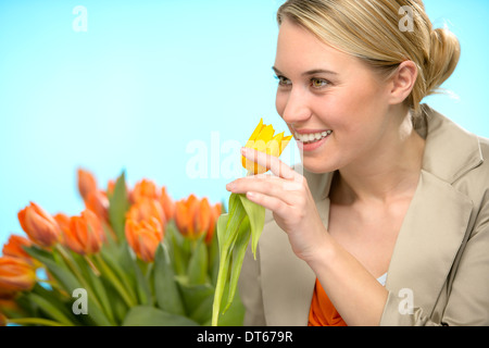 Donna odorare un tulipano giallo fiori di primavera sorridente Foto Stock