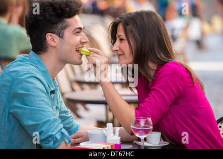 Coppia giovane mangiare amaretto al cafe' sul marciapiede, Parigi, Francia Foto Stock