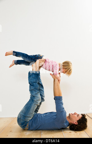 Studio shot di padre sollevando la figlia mentre giacente sul retro Foto Stock