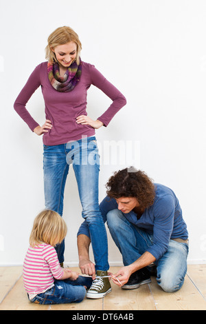 Ritratto in studio di madre avente lacci delle scarpe legati Foto Stock