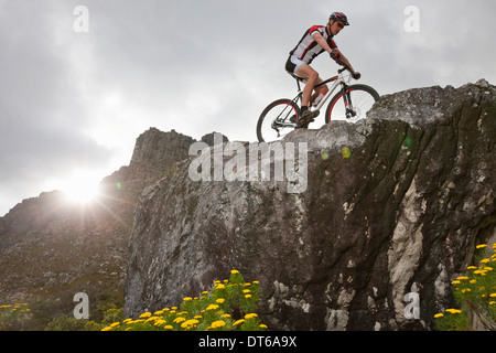 Giovane uomo mountain bike sulla parte superiore di formazione di roccia Foto Stock