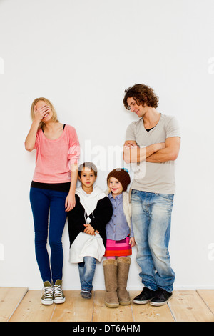 Studio shot del giovane con il figlio e la figlia a sovradimensionare i vestiti Foto Stock