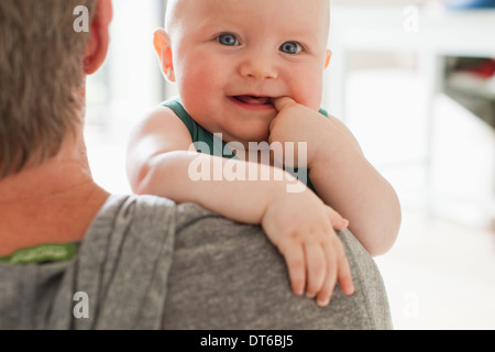 Padre bambino portando la figlia con il dito in bocca Foto Stock