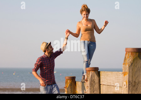 Giovane donna in equilibrio su pennelli azienda mano d'uomo Foto Stock