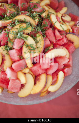 Preparati organici farm stand alimentari di partito. Frutta estiva insalata di anguria, pesche e menta. Foto Stock