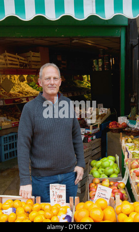 Fruttivendolo davanti alla sua pressione di stallo Foto Stock