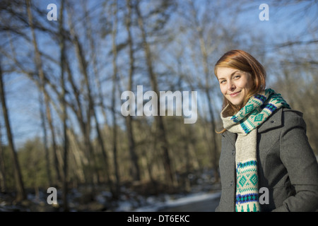 Una giovane donna in un bosco su un giorno d'inverno. Indossando un luminoso lavorata a maglia Sciarpa a motivi geometrici. Foto Stock