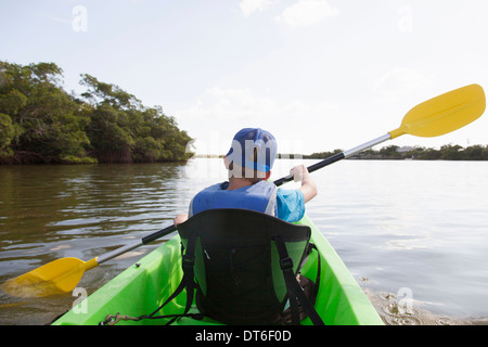 Ragazzo giovane paddling canoe sul tranquillo fiume Foto Stock