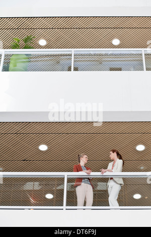 Femmina di due colleghi di lavoro prendendo una pausa sul balcone di office Foto Stock