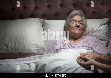 Giovane donna holding sleeping senior donna di mano Foto Stock