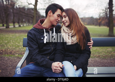 Coppia giovane la condivisione di un momento di gara mentre è seduto su una panchina nel parco. Teenage asian giovane all'aperto nel parco. Foto Stock