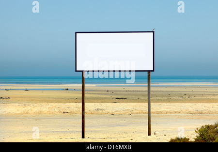 Un grande segno su una spiaggia idilliaca con nessun testo e un piccolo uccello - Un grigio meridionale Shrike - arroccato su un angolo. Foto Stock