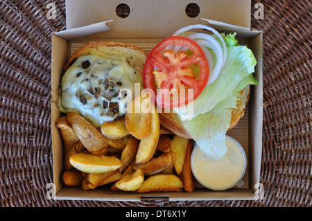 Hamburger con patatine fritte e formaggio fuso funghi. Cibo da asporto in imballaggio. Foto Stock