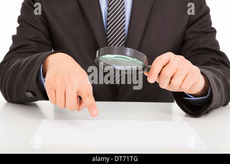 Imprenditore puntando attraverso una lente di ingrandimento per documenti su bianco Foto Stock