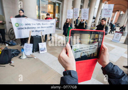 Londra, Regno Unito. Xi Febbraio 2014. La diffusione del messaggio utilizzando i nuovi media - mi-pad su Youtube. Diritti umani contestatori dall'Algeria Campagna di Solidarietà (ASC) raccogliere al di fuori del London Stock Exchange per aumentare la consapevolezza su quello che chiamano "la repressione regime algerino' e i suoi legami con i potenti multinazionali come BP appassionati di sue riserve di gas. Credito: Guy Bell/Alamy Live News Foto Stock