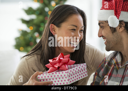 Un uomo in un Babbo Natale hat. A casa. Un albero di Natale decorato. Foto Stock