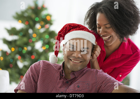 Un uomo in un Babbo Natale hat. A casa. Un albero di Natale decorato.
