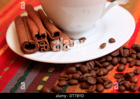 Bastoncini di cannella con caffè sbriciolate e tazza bianca Foto Stock