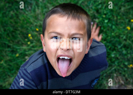 7-anno-vecchio ragazzo tirando la sua lingua Foto Stock