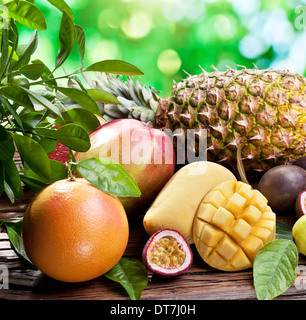 Frutti Esotici su un tavolo di legno con fogliame verde sullo sfondo. Foto Stock