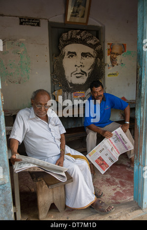 Gli uomini la lettura quotidiani di fronte ad una grande immagine di Che Guevara in un partito comunista office, Fort Cochin, Kochi (Cochin), Kerala, India Foto Stock