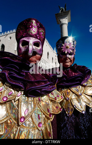 Due persone mascherate che pongono al Carnevale di Venezia con Palazzo Ducale sullo sfondo Foto Stock