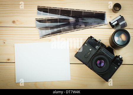 Vecchia fotocamera retrò e rotolo pellicola su tavole di legno. Foto Stock