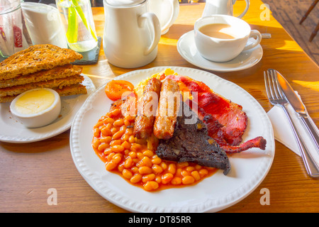 La completa prima colazione inglese bacon uova strapazzate funghi salsiccia fagioli black pudding e pomodori fritti tea toast e burro Foto Stock