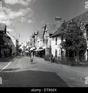 Foto storiche da anni cinquanta che mostra un ciclista nella parte superiore del villaggio di Porlock high street, Somerset, Inghilterra. Foto Stock