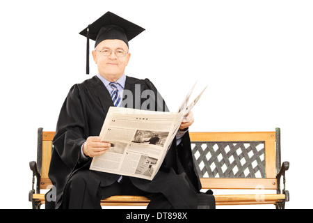 Uomo maturo in abito di graduazione leggendo un giornale seduto sul banco di lavoro Foto Stock