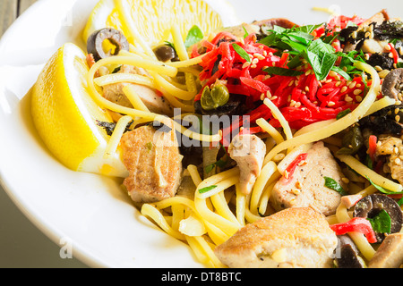 Linguine con tonno ahi e rabboccato con zenzero sott'aceto, olive nere, i semi di sesamo, prezzemolo, nori e basilico, servito con spicchi di limone Foto Stock