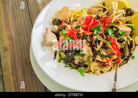 Linguine con tonno ahi e rabboccato con zenzero sott'aceto, olive nere, i semi di sesamo, prezzemolo, nori e basilico, servito con spicchi di limone Foto Stock