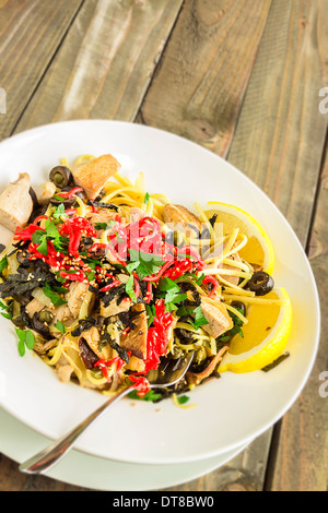 Linguine con tonno ahi e rabboccato con zenzero sott'aceto, olive nere, i semi di sesamo, prezzemolo, nori e basilico, servito con spicchi di limone Foto Stock