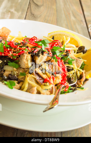 Linguine con tonno ahi e rabboccato con zenzero sott'aceto, olive nere, i semi di sesamo, prezzemolo, nori e basilico, servito con spicchi di limone Foto Stock