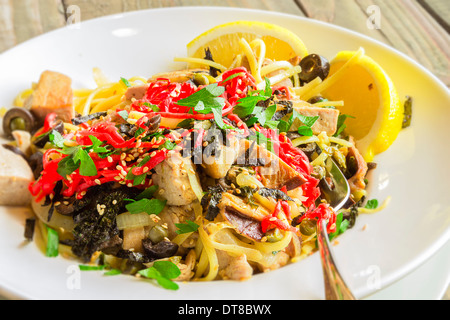 Linguine con tonno ahi e rabboccato con zenzero sott'aceto, olive nere, i semi di sesamo, prezzemolo, nori e basilico, servito con spicchi di limone Foto Stock