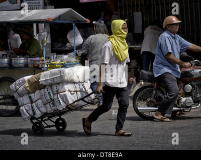 Thailandia scena di strada con un uomo che sta utilizzando un carrello a mano per offrire beni di mercato. Thailandia SUDEST ASIATICO Foto Stock
