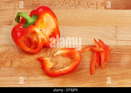 Peperone rosso affettato su un legno di faggio preparazione alimentare board Foto Stock