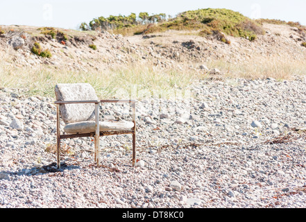 Vecchi e consunti sedia fuori su una terra coperta con piccole pietre Foto Stock