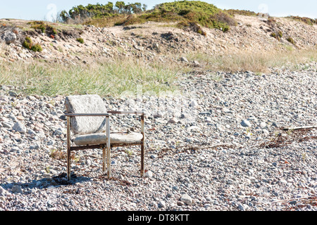 Vecchi e consunti sedia fuori su una terra coperta con piccole pietre Foto Stock