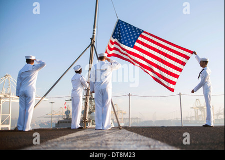 US Navy marinai alzare la bandiera americana durante la mattina i colori a bordo della portaerei USS Harry Truman Gennaio 25, 2014 in Jebel Ali, Emirati Arabi Uniti. Foto Stock