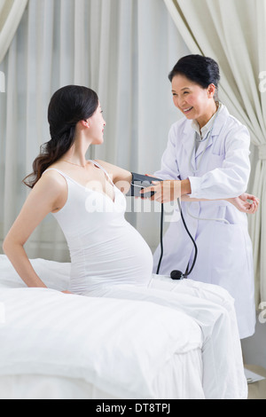Medico a parlare con una donna in stato di gravidanza Foto Stock