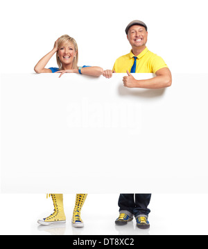 Sorridenti l uomo e la donna in piedi dietro un grande vuoto bianco segno con spazio di copia Foto Stock