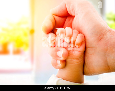 I genitori mani del bambino in mano bright house. Foto Stock