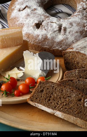 In stile country del pane di segale, il parmigiano e i pomodori ciliegia sul bordo di taglio Foto Stock