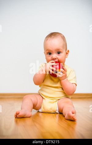 Baby eating apple giacente sul piano - uno stile di vita sano Foto Stock