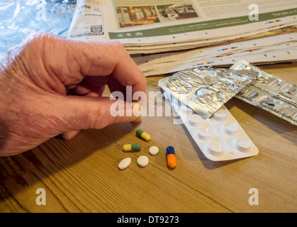 Anziani mano d'uomo con selezione di pillole, compresse e capsule. Dose giornaliera di farmaco. Foto Stock
