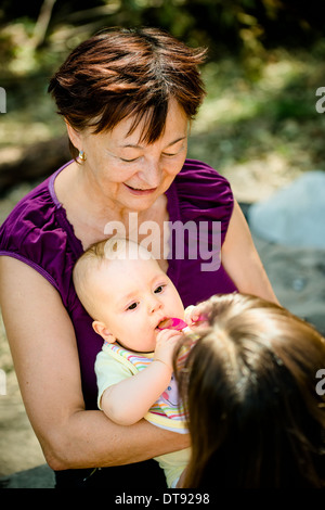 Madre che nutre il suo bambino con il cucchiaio, nonna è aiutare Foto Stock